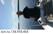 Vertical video of teenage girl sitting on bow of riding motorboat, speedboat moving on lake water surface. Стоковое видео, видеограф Кекяляйнен Андрей / Фотобанк Лори