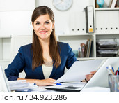 Smiling woman working with papers and laptop in office. Стоковое фото, фотограф Яков Филимонов / Фотобанк Лори