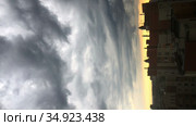 Vertical time lapse of moving thunder clouds over urban roofs of buildings, sunset light. Стоковое видео, видеограф Кекяляйнен Андрей / Фотобанк Лори