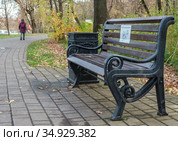 Москва. Осень 2020. Скамья с надписью "Соблюдайте социальную дистанцию" на аллее парка "Останкино". Вдалеке видна одинокая женская фигурка. Стоковое фото, фотограф Наталья Николаева / Фотобанк Лори