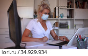 Female office worker in protective medical mask is standing with documents before signing it in office. Стоковое видео, видеограф Яков Филимонов / Фотобанк Лори