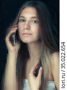 Portrait of young blonde woman with phone hands behind the window glass with raindrops. Стоковое фото, фотограф Сергей Пристяжнюк (Serg Zastavkin) / Фотобанк Лори