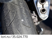 Screw nail puncturing motorcycle tire. Close up view at rear wheel. Стоковое фото, фотограф Кекяляйнен Андрей / Фотобанк Лори