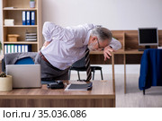 Old male employee suffering from radiculitis at workplace. Стоковое фото, фотограф Elnur / Фотобанк Лори