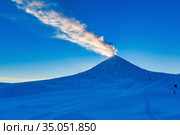 Kamchatka Peninsula, winter eruption active Volcano Klyuchevskaya Sopka at sunset, golden hour. Plume of ash, gas in blue sky. Стоковое фото, фотограф А. А. Пирагис / Фотобанк Лори