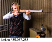 Confident shooter sighting in or zeroing shotgun in shooting gallery. Стоковое фото, фотограф Яков Филимонов / Фотобанк Лори
