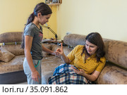 A child or girl turns to an adult woman who is viewing information on her phone  Девочка, дочь обращается к женщине, матери, которая увлечена информацией в телефоне и отказывает в общении ребёнку. Стоковое фото, фотограф Владимир Ушаров / Фотобанк Лори