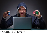 Young man wearing a hoodie sitting in front of a laptop computer. Стоковое фото, фотограф Elnur / Фотобанк Лори