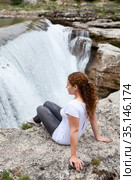 Pretty woman sitting on rock and enjoying of the cascade of Cijevna river. It is called Montenegrin Niagara Falls. Surroundings of Podgorica city. Montenegro, Balkans, Europe. Стоковое фото, фотограф Кекяляйнен Андрей / Фотобанк Лори