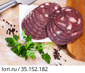 Close up of Spanish smoked blood sausage on white plate on wooden table. Стоковое фото, фотограф Яков Филимонов / Фотобанк Лори