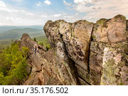 man and woman tourists on the rocky peak Aleksandrovskaya Sopka against the background of the city of Zlatoust on a summer sunny day. Стоковое фото, фотограф Акиньшин Владимир / Фотобанк Лори
