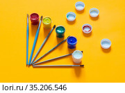 На желтом фоне разложены кисти и баночки с гуашью, хаотично разложены крышечки. Стоковое фото, фотограф Иванов Алексей / Фотобанк Лори