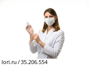 Девушка врач натягивает прозрачные медицинские перчатки на руки и смотрит в кадр. Стоковое фото, фотограф Иванов Алексей / Фотобанк Лори
