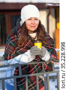 Woman drinking hot coffee from paper cup wrapping with red woollen scarf, wintertime, urban street. Стоковое фото, фотограф Кекяляйнен Андрей / Фотобанк Лори