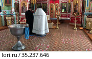 Priest and his assistant stand close to the baptistery. It is sacrament of initiation into the Christian church. Russia (2021 год). Редакционное видео, видеограф Кекяляйнен Андрей / Фотобанк Лори