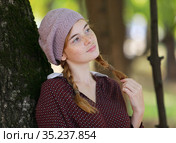 Cute freckled girl with pigtails leaned against a tree. Стоковое фото, фотограф Алексей Кузнецов / Фотобанк Лори