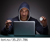 Young man wearing a hoodie sitting in front of a laptop computer. Стоковое фото, фотограф Elnur / Фотобанк Лори