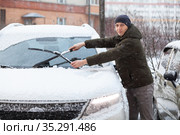 Caucasian driver cleans windshield and removes snow from rubber wipers of his car. Стоковое фото, фотограф Кекяляйнен Андрей / Фотобанк Лори