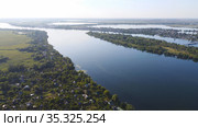 Drone fly over waving river of blue color surrounded by local village with various buildings and Wetland and marsh habitat with a reedbed of Common Reed aerial view. (2020 год). Редакционное фото, фотограф Nataliia Zhekova / Фотобанк Лори