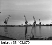 Несколько портальных кранов загружают корабли прибывшие в речную гавань, вид на грузовой порт с баржами, фрагмент судна на переднем плане, Тикси, Якутия, 1962. Стоковое фото, фотограф Варфоломей Тетерин / Фотобанк Лори