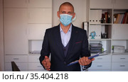 Portrait of positive business man in protective mask with folder of documents at office. Стоковое видео, видеограф Яков Филимонов / Фотобанк Лори