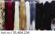 Variety of natural wigs and hairpieces hanging on stand in specialized store. Стоковое видео, видеограф Яков Филимонов / Фотобанк Лори