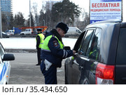 Инспектор дорожно-патрульной службы полиции проверяет документы водителя остановленного автомобиля (2016 год). Редакционное фото, фотограф Free Wind / Фотобанк Лори