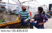 Two latin american male and female workers in protective face masks working on forklift loader at farm and talking. Стоковое видео, видеограф Яков Филимонов / Фотобанк Лори