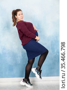 Portrait of fashionable pregnant woman wearing in brown blouse and blue skirt against blue studio background. Стоковое фото, фотограф Кекяляйнен Андрей / Фотобанк Лори