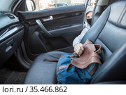 A thief, a criminal, thrust his hand out of the car door and takes a backpack, steals private property. Стоковое фото, фотограф Кекяляйнен Андрей / Фотобанк Лори
