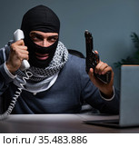 Terrorist burglar with gun working at computer. Стоковое фото, фотограф Elnur / Фотобанк Лори