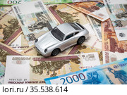 Игрушечный автомобиль стоит на российских деньгах. Автокредит и траты на обслуживание автомобиля. Стоковое фото, фотограф Павел Сапожников / Фотобанк Лори
