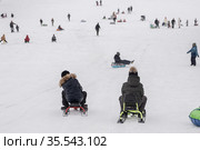 Дети катятся вниз с большой горы на снегокатах. Стоковое фото, фотограф Кузин Алексей / Фотобанк Лори