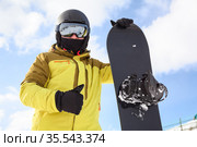 Snowboard and snowboarder with thumb up. Man wearing helmet, goggles and gloves. Extreme winter sport. Стоковое фото, фотограф Кекяляйнен Андрей / Фотобанк Лори
