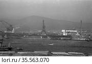 Гавань озера Байкал с погрузочными кранами установленными на побережье порта, брёвна подготовленный к к сплаву по воде на переднем плане, моторная лодка проплывает неподалёку от них, Восточная Сибирь, 1964 год. Стоковое фото, фотограф Варфоломей Тетерин / Фотобанк Лори