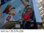 Женщина идет по улице в центре города Москвы на фоне граффити на фасаде здания с изображением сценки из советского фильма "Офицеры", Россия (2021 год). Редакционное фото, фотограф Николай Винокуров / Фотобанк Лори