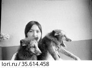 Два серых зверька в руках сотрудницы фермы по выращиванию животных для добычи ценных пород меха, девушка стоит в помещении и показывает песцов, Лорино, Чукотка, 1970. Редакционное фото, фотограф Варфоломей Тетерин / Фотобанк Лори