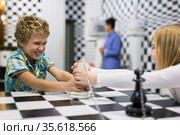 Boy adn girl solving puzzle together in room stylized like chessboard. Стоковое фото, фотограф Яков Филимонов / Фотобанк Лори