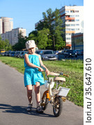Unhappy preschool girl carrying her bicycle on asphalt lane holding steering wheel. Стоковое фото, фотограф Кекяляйнен Андрей / Фотобанк Лори