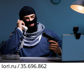 Terrorist burglar with gun working at computer. Стоковое фото, фотограф Elnur / Фотобанк Лори