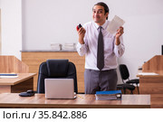 Young male employee stapling paper in the office. Стоковое фото, фотограф Elnur / Фотобанк Лори