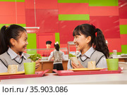 Two girls talking at lunch in school cafeteria. Стоковое фото, агентство Ingram Publishing / Фотобанк Лори