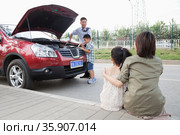 Mother and Daughter Watch as Father and Son Try to Fix the Car. Стоковое фото, агентство Ingram Publishing / Фотобанк Лори