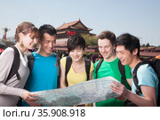 Five people looking at map with Tiananmen Square in background. Стоковое фото, агентство Ingram Publishing / Фотобанк Лори