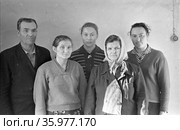 Четыре женщины разных возрастов и мужчина средних лет стоят в помещении, коллективный портрет на фоне белой стены с розеткой, Якутия, ноябрь 1963, база Холбос. Стоковое фото, фотограф Варфоломей Тетерин / Фотобанк Лори