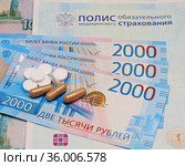 Российский полис обязательного медицинского страхования, денежные купюры и лекарства в таблетках (2021 год). Редакционное фото, фотограф Цибаев Алексей / Фотобанк Лори