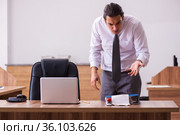 Young male employee stapling paper in the office. Стоковое фото, фотограф Elnur / Фотобанк Лори