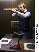 Confident shooter sighting in or zeroing shotgun in shooting gallery. Стоковое фото, фотограф Яков Филимонов / Фотобанк Лори