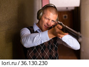 Confident shooter sighting in or zeroing shotgun in shooting gallery. Стоковое фото, фотограф Яков Филимонов / Фотобанк Лори