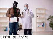 Masked man burglar bribing old doctor for getting vaccine. Стоковое фото, фотограф Elnur / Фотобанк Лори